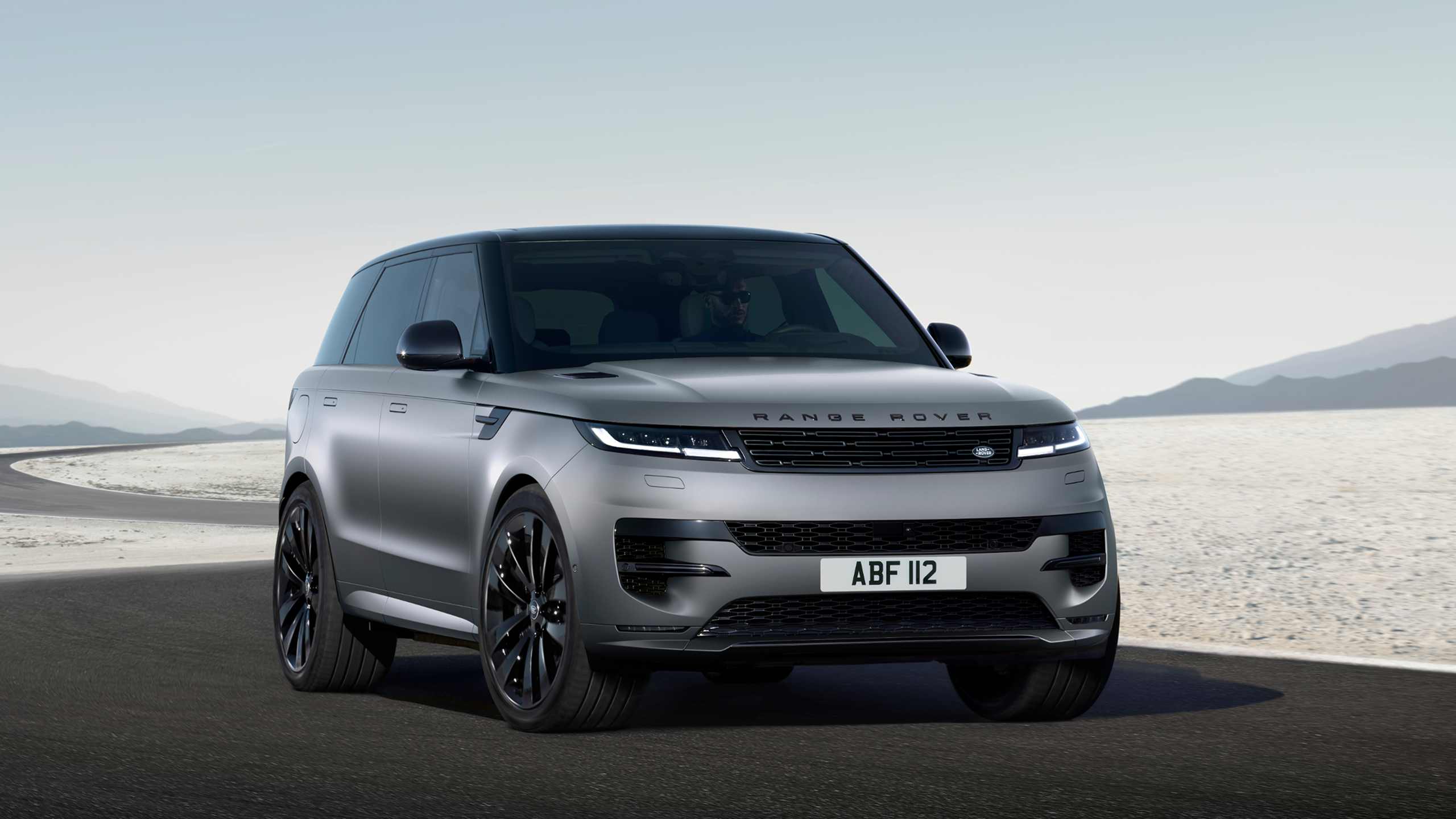 Range Rover Sport in Eiger Grey driving through a road in a desert area.